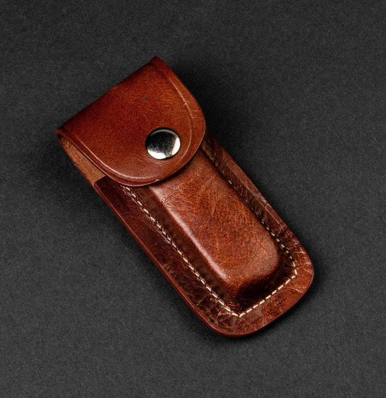 Brown leather pouch with a button on a dark gray background