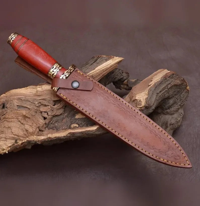 Knife with red handle and brown leather sheath on wooden background