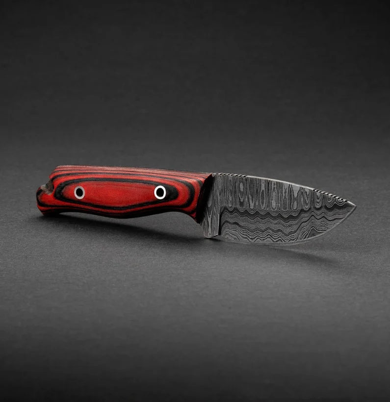 Knife with a red and black handle on a gray background