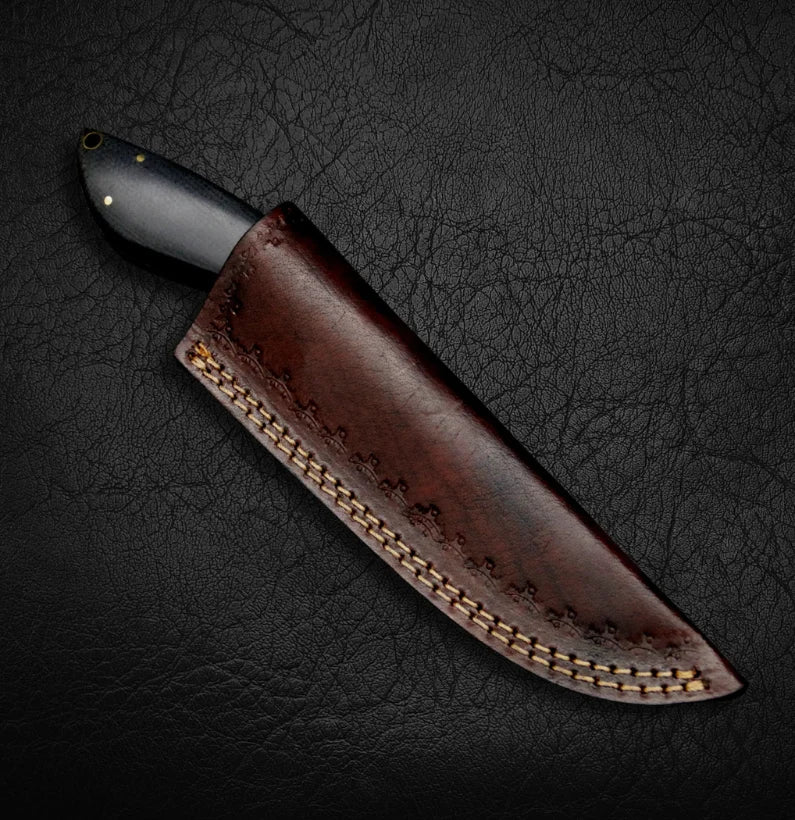 Knife with a brown leather sheath on a dark textured surface